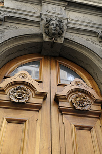 Wooden door with carved figurine in stone above it. France by Kevin Oke