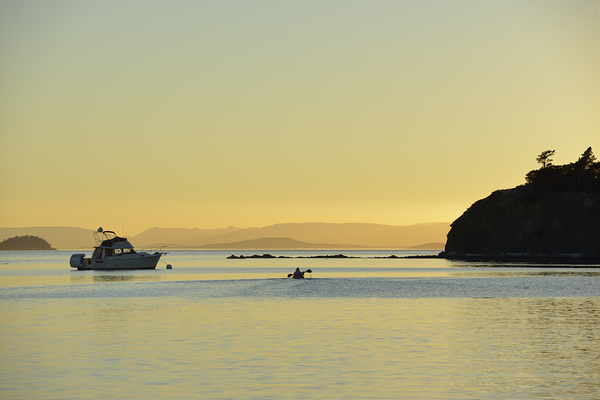 Kayaker and motor boat at anchor in Fox Cove. Sucia Island Print