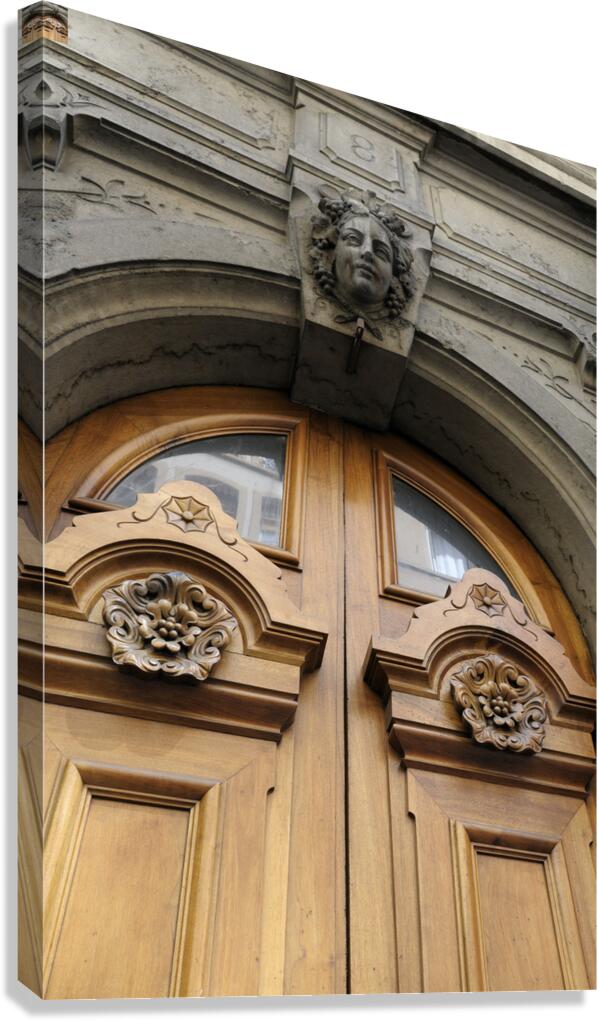 Wooden door with carved figurine in stone above it. France Canvas Print